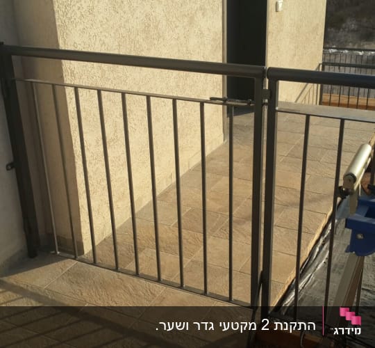 שער וגדר ממתכת עם סורגים אנכיים במרפסת מרוצפת